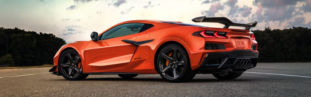 Orange Chevrolet Corvette sports car parked on a track at sunset.