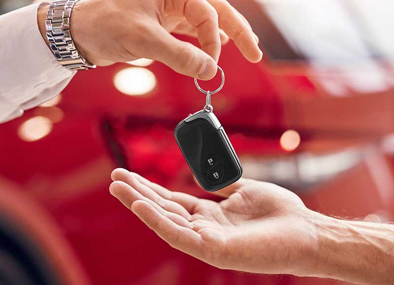 A man hands a car key to another person, indicating a transfer of ownership or responsibility.